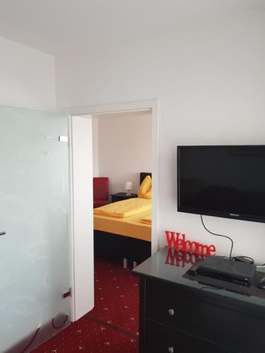 a room with a television and a bedroom with a bed at Panorama Hotel Pension Frohnau in Bad Sachsa
