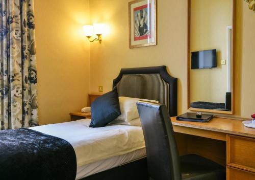 a hotel room with a bed and a desk with a laptop at Cairndale Hotel & Spa in Dumfries