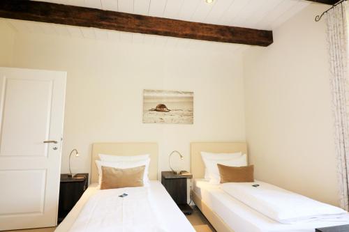 two beds in a white room with two lamps at Apartments Lille Hus in Sankt Peter-Ording
