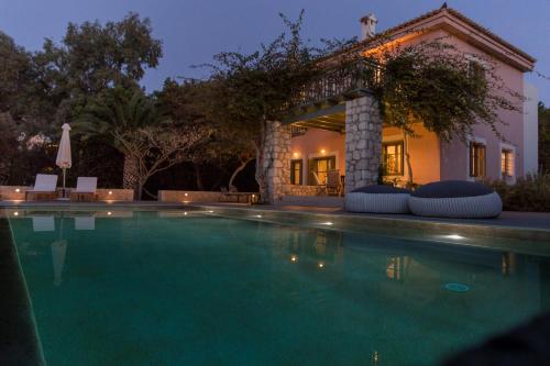 a swimming pool in front of a house at Villa Iris - Luxury traditional beachfront villa with swimming pool in Koilás