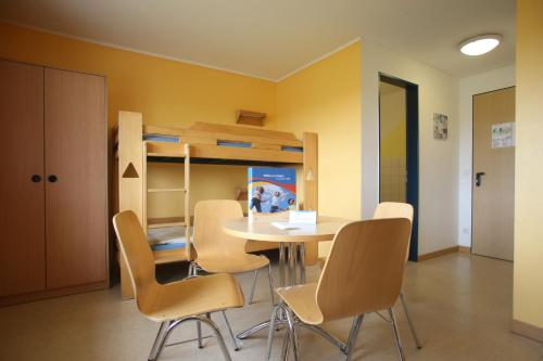 a dining room with a table and chairs and a bunk bed at Jugendherberge Westerland in Westerland (Sylt)