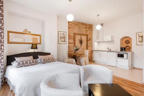 a white bedroom with a bed and a kitchen at Vilnius Apartments in Vilnius