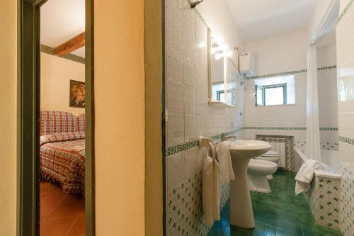 a bathroom with a sink and a toilet and a bed at Fattoria di Casalappi in Campiglia Marittima