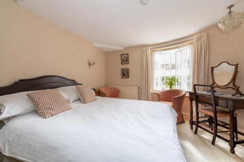 a bedroom with a bed and a desk and a window at Royal Glen Hotel in Sidmouth