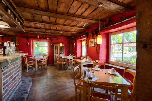 un ristorante con tavoli e sedie in legno e pareti rosse di Hotel & Gasthof Zur Linde a Middelhagen