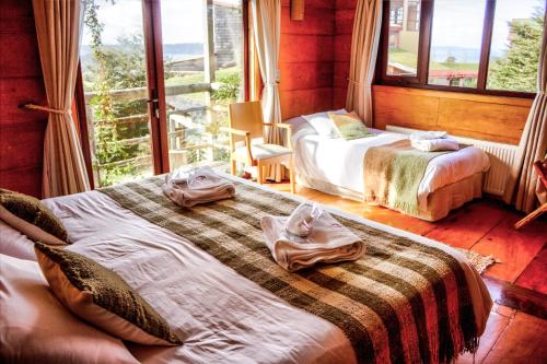 a bedroom with two beds and a large window at Hotel Parque Quilquico in Castro