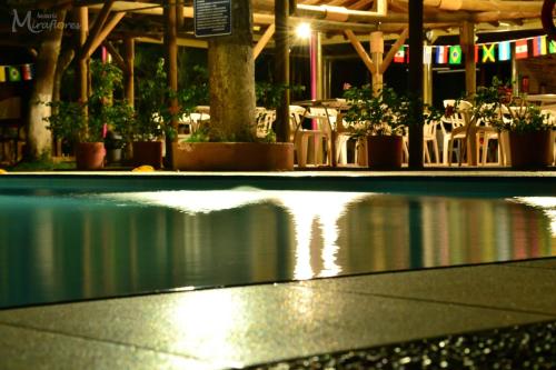 a pool of water in front of a building with tables and chairs at Hostería Miraflores in Liborina