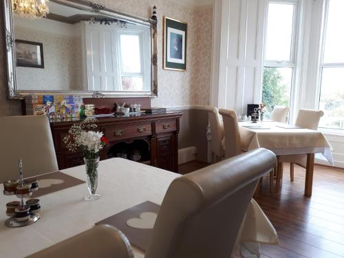 ein Esszimmer mit einem Tisch, Stühlen und einem Spiegel in der Unterkunft Min y Don Guest House in Llanfairfechan
