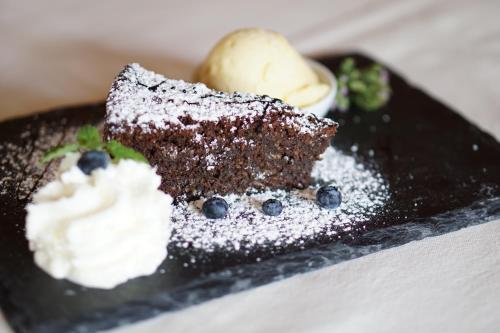 a black plate with a piece of cake and ice cream at Mahorko Wein Wellness Wasserbüffel in Glanz an der Weinstraße 