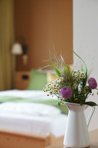 a white vase filled with flowers on a table at Mahorko Wein Wellness Wasserbüffel in Glanz an der Weinstraße 