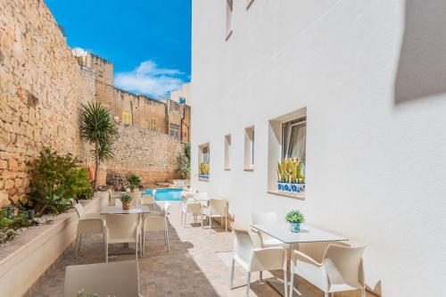 a patio with tables and chairs and a pool at Palazzo Violetta Boutique Hotel in Sliema