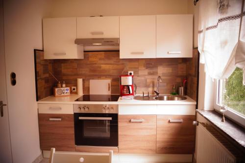 a small kitchen with white cabinets and a sink at FeWo Düver in Loxstedt