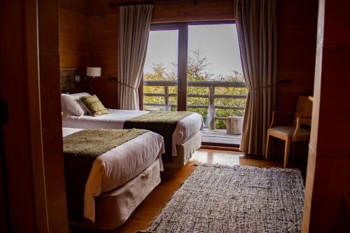a bedroom with two beds and a window with a view at Hotel Parque Quilquico in Castro