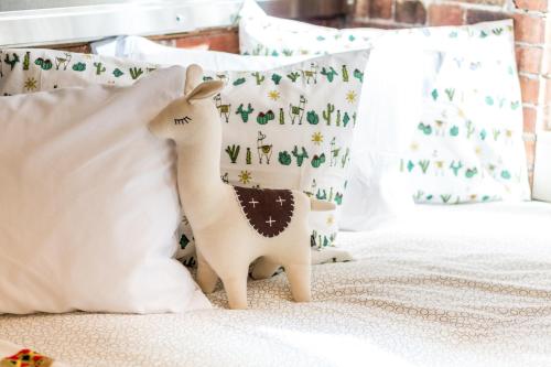 a stuffed llama toy sitting on a bed with pillows at INITIAL - LOFT LAMA - Centre-Ville de Québec in Quebec City