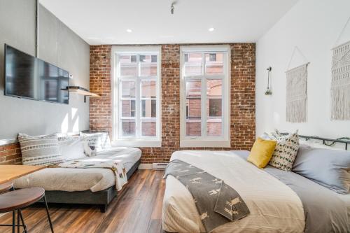 a bedroom with two beds and a brick wall at INITIAL - LOFT LAMA - Centre-Ville de Québec in Quebec City