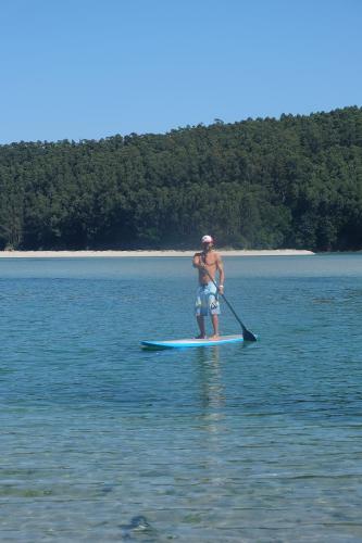 a man standing on a paddle board in the water at Casa en primera linea de playa en Pantin!! in Pantín