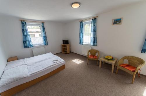 a bedroom with a bed and two chairs and a table at Penzion Kosky in Hamr