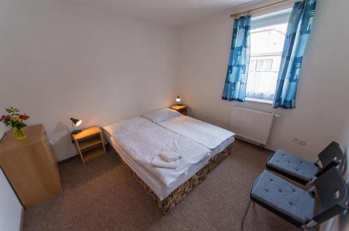 a bedroom with a bed and a chair and a window at Penzion Kosky in Hamr