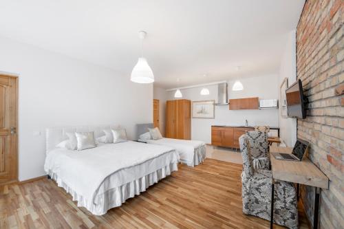 a white bedroom with two beds and a kitchen at Vilnius Apartments in Vilnius