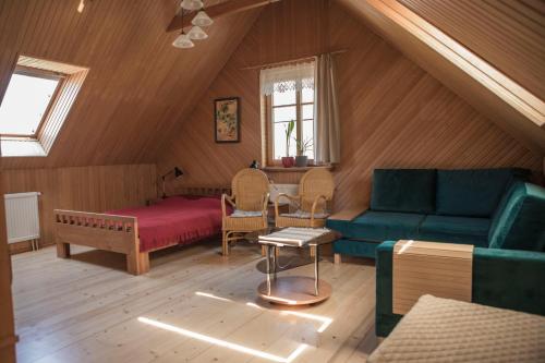 a living room with a couch and a bed in a attic at Nidos Rojus in Nida