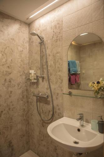 a bathroom with a shower and a sink and a mirror at Nidos Rojus in Nida