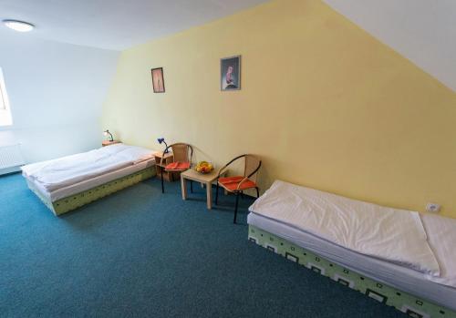 a room with two beds and a table and chairs at Penzion Kosky in Hamr