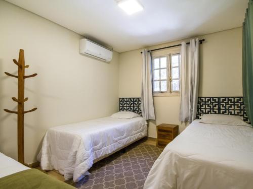 a bedroom with two beds and a window at Villa Vintage Campos - Piscina e opções de suites com hidromassagem in Campos do Jordão
