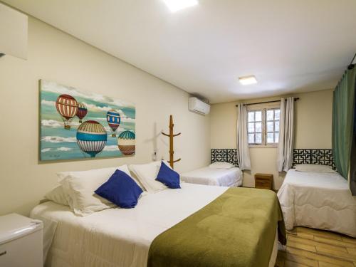 a bedroom with two beds and a painting of hot air balloons at Villa Vintage Campos - Piscina e opções de suites com hidromassagem in Campos do Jordão