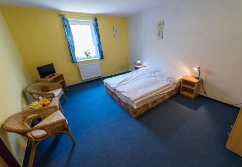 a bedroom with a bed and a chair and a window at Penzion Kosky in Hamr