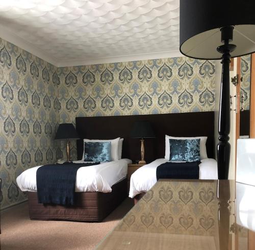 a hotel room with two beds and a table at Virginia Court Hotel in Cromer