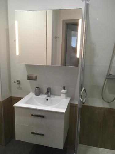łazienka z białą umywalką i lustrem w obiekcie Apartament Silver Klifowa w Rewalu