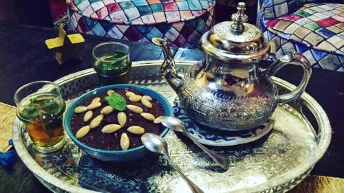 a tray with a tea pot and a bowl of peanuts at Riad La Porte du Bouregreg in Salé