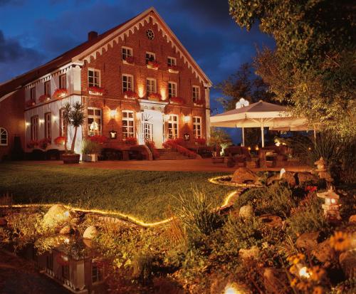 a large building with lights in front of a yard at Hotel Landhaus Steinfeld in Greetsiel