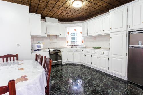 a kitchen with white cabinets and a table in it at Apartamentos Oliveira in Madalena