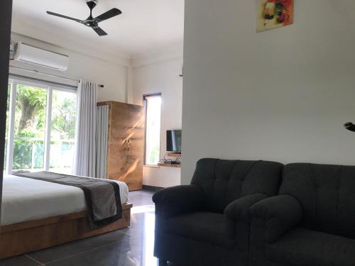 a bedroom with a couch and a bed and a window at Rankk Stays in Arambol