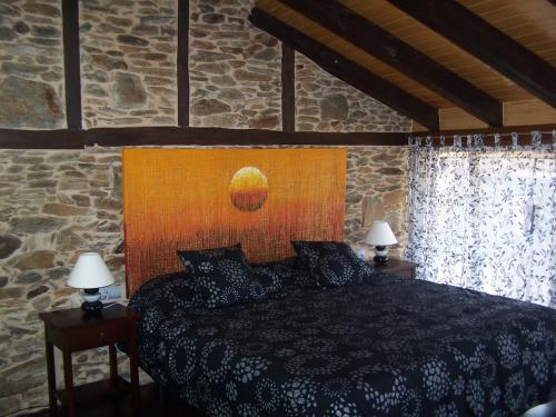 a bedroom with a bed in a stone wall at Alojamiento Luz de Hadas in Sampil