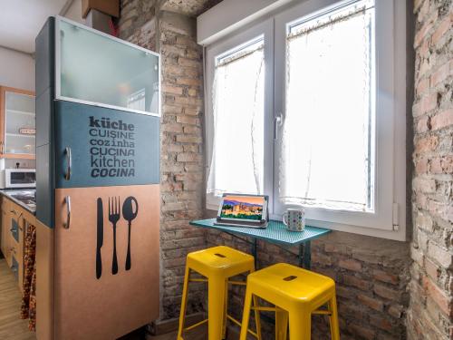 a kitchen with a refrigerator and two yellow stools at Apartamento el Purche in Granada