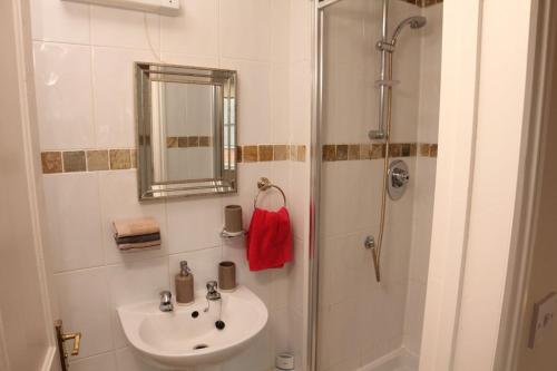 a bathroom with a sink and a shower with a mirror at Evee's Pebbles 1 in Eastbourne