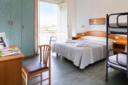 a bedroom with a bed and a desk with a chair at Hotel Mara in Rimini