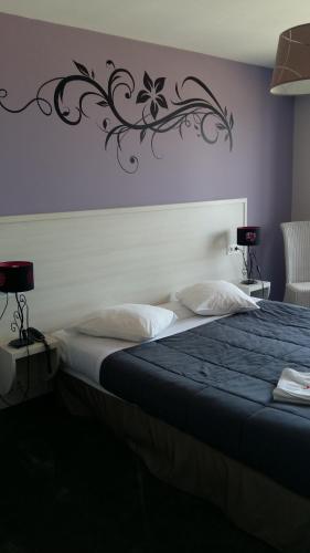 ein Schlafzimmer mit einem großen Bett mit einem schwarzen Reben an der Wand in der Unterkunft Hotel des Thermes et du Casino in Luc-sur-Mer