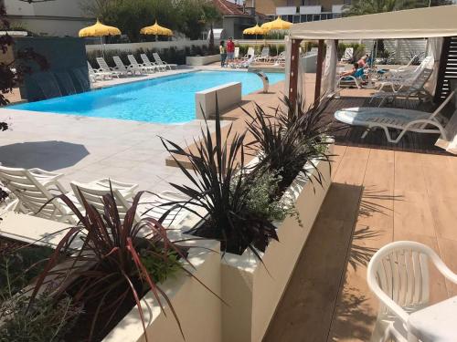 una piscina con sedie e una persona seduta su un patio di Hotel Milanese a Rimini
