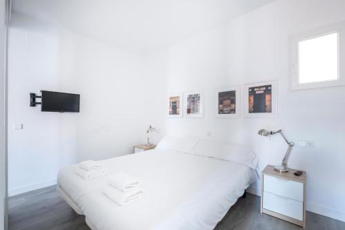 een witte slaapkamer met een bed en een televisie bij La Latina Rastro Boutique in Madrid