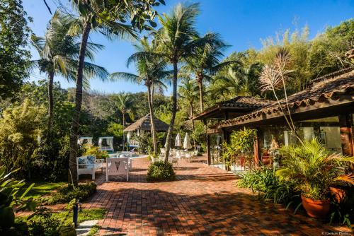 un complejo con palmeras y una pasarela de ladrillo en Barracuda Eco Resort Búzios, en Búzios