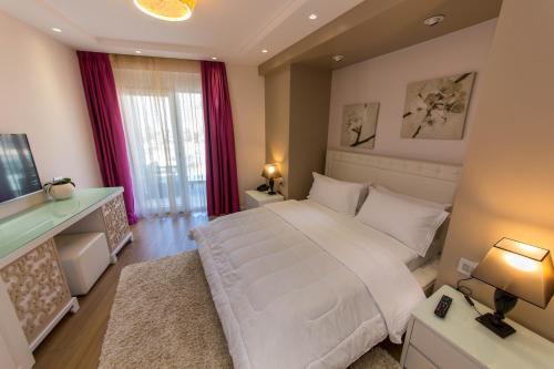 a bedroom with a large white bed and a television at Demi Hotel in Sarandë
