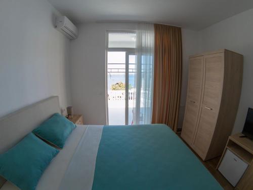 a bedroom with a bed and a door to a beach at Queen Apartments & Rooms in Dobra Voda