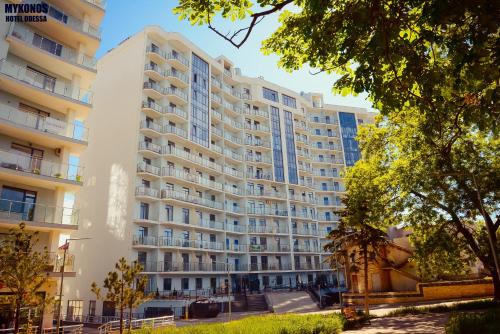 a large white building with trees in front of it at Mykonos Hotel Apart - Maestro in Odesa