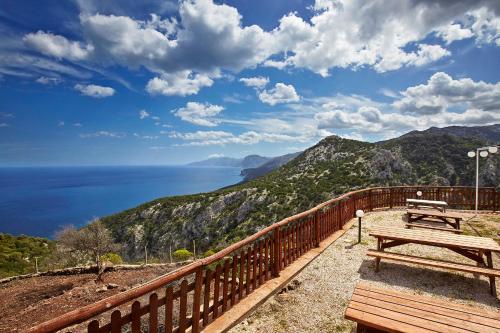 a wooden bench sitting on top of a hill overlooking the ocean at Agriturismo Codula Fuili in Cala Gonone