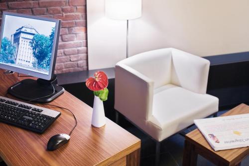 a desk with a computer monitor and a white chair at Mövenpick Hotel Hamburg City in Hamburg