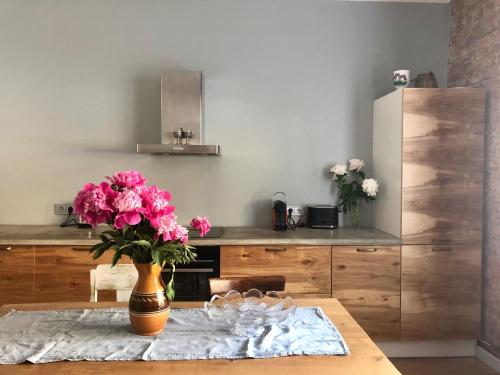 a kitchen with a table with a vase of pink flowers at Sophisticated art deco near sea, centre and parks in Ventspils