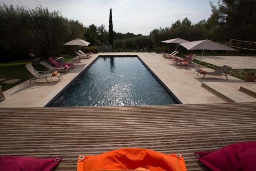 uma piscina com cadeiras e guarda-sóis num quintal em Mas des Avelines em Le Castellet